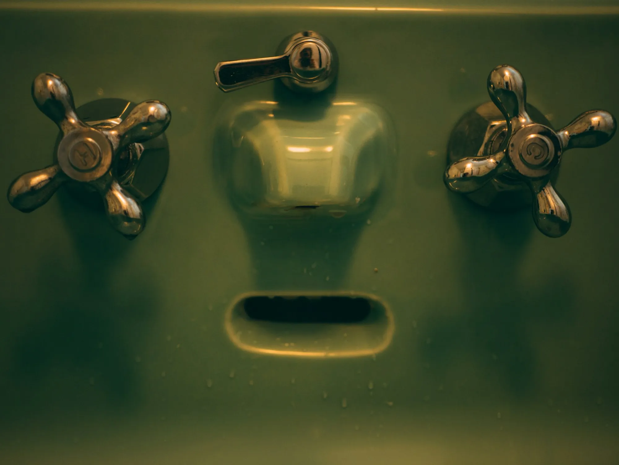 Aged brass tap handles on a stained basin