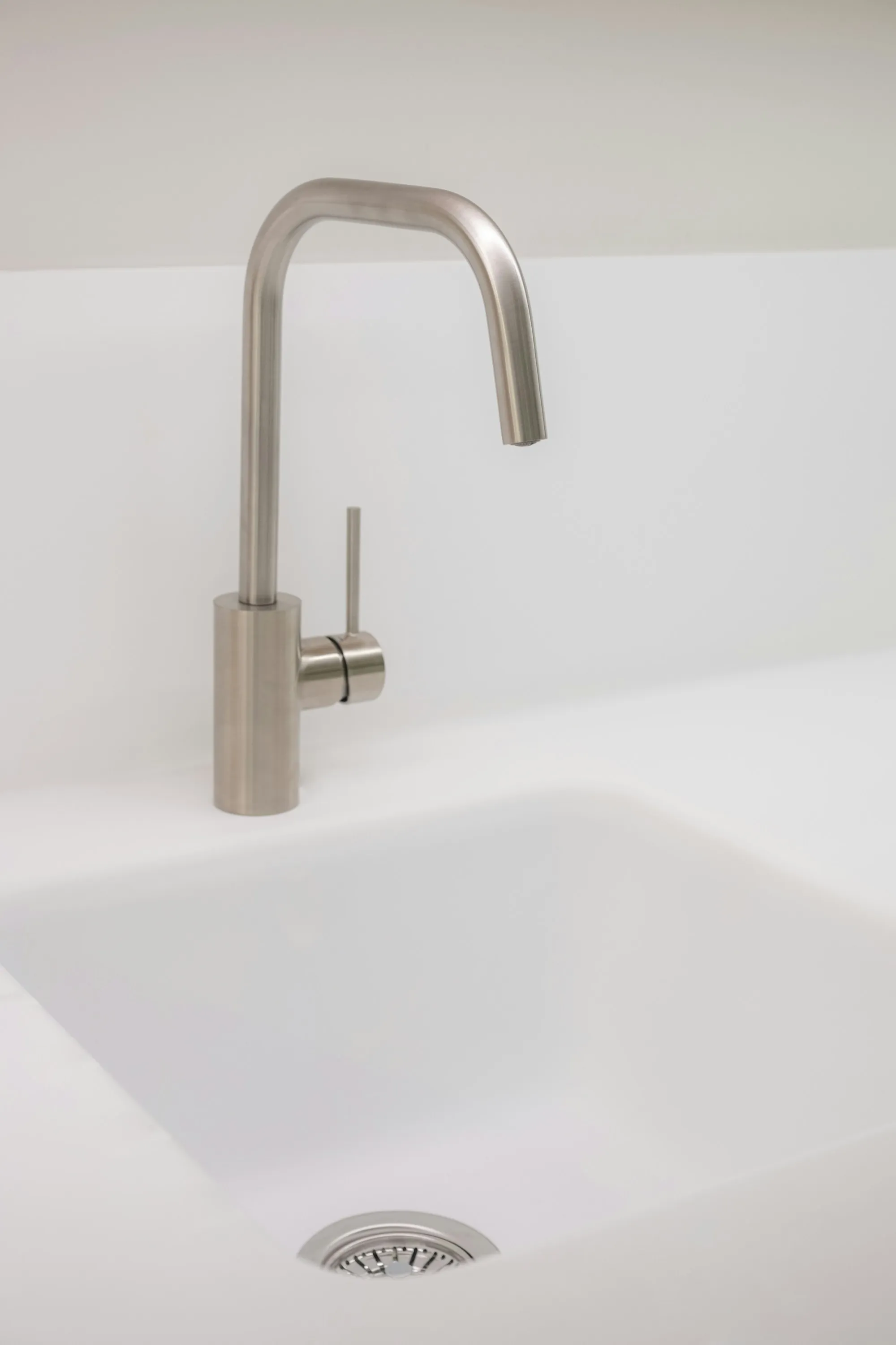 Brushed steel faucet over a white sink