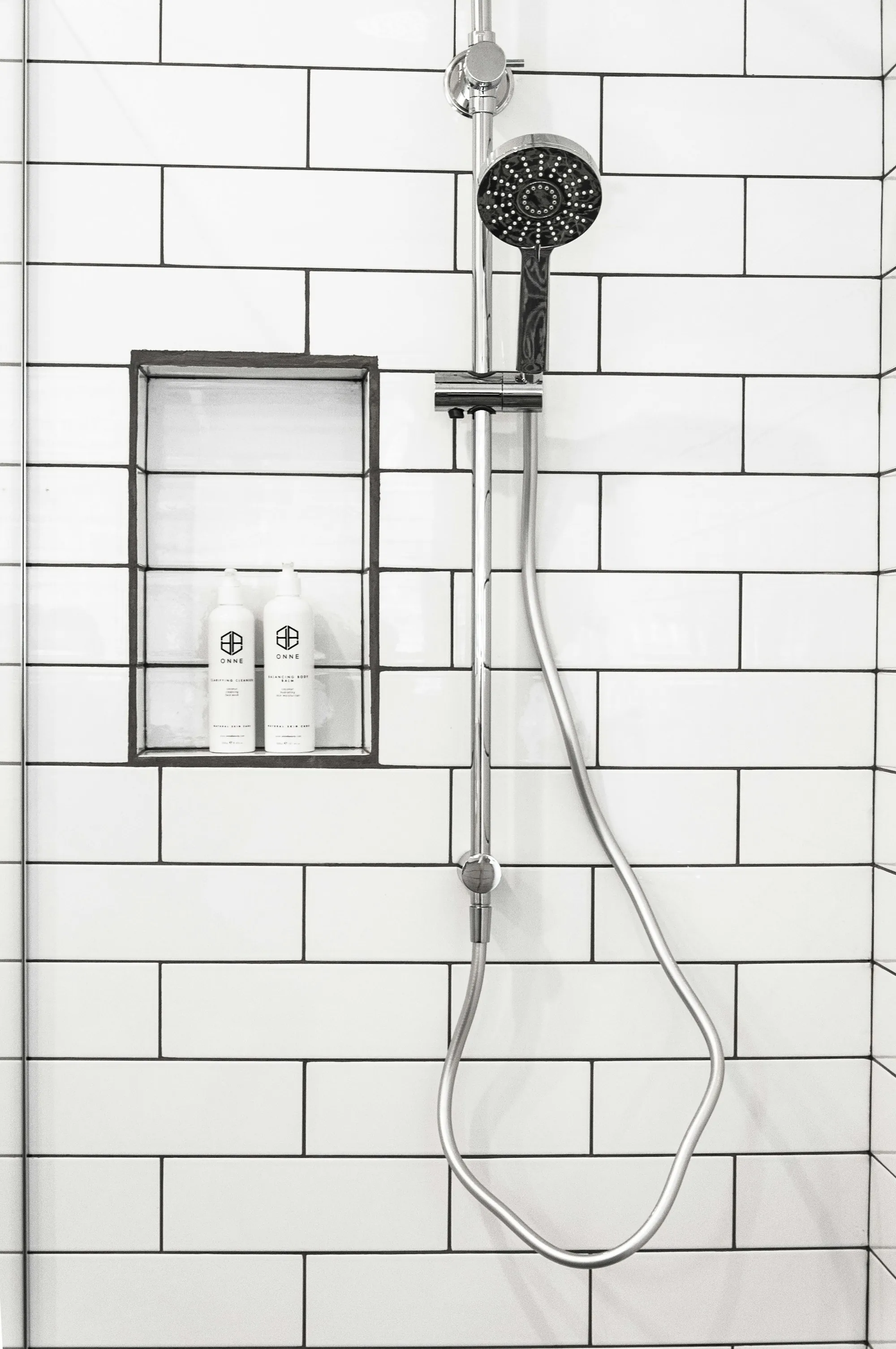 Shower with a handheld head on white tile